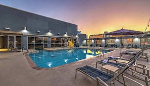 A swimming pool with lounge chairs and a building with large windows. - Spacious Vegas Strip View Balcony Full Kitchen (Las Vegas)