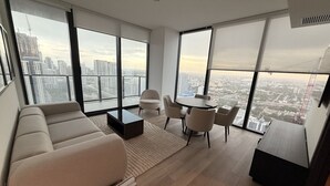 A modern living room with a sofa, chairs, a coffee table, and a dining table. Large windows offer a city view. - E4010A - Modern 1BR with Balcony & West View in Downtown Miami (Miami Beach)