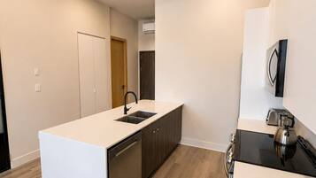 Une cuisine moderne dotée d’un îlot central, d’un lave-vaisselle encastré et d’une cuisinière noire.
