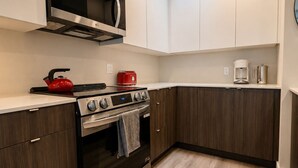Una cocina moderna con electrodomésticos integrados, microondas, estufa y cafetera.