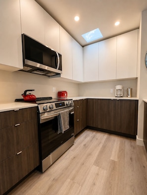 A modern kitchen with built-in appliances, a microwave, a stove, and a coffee maker.