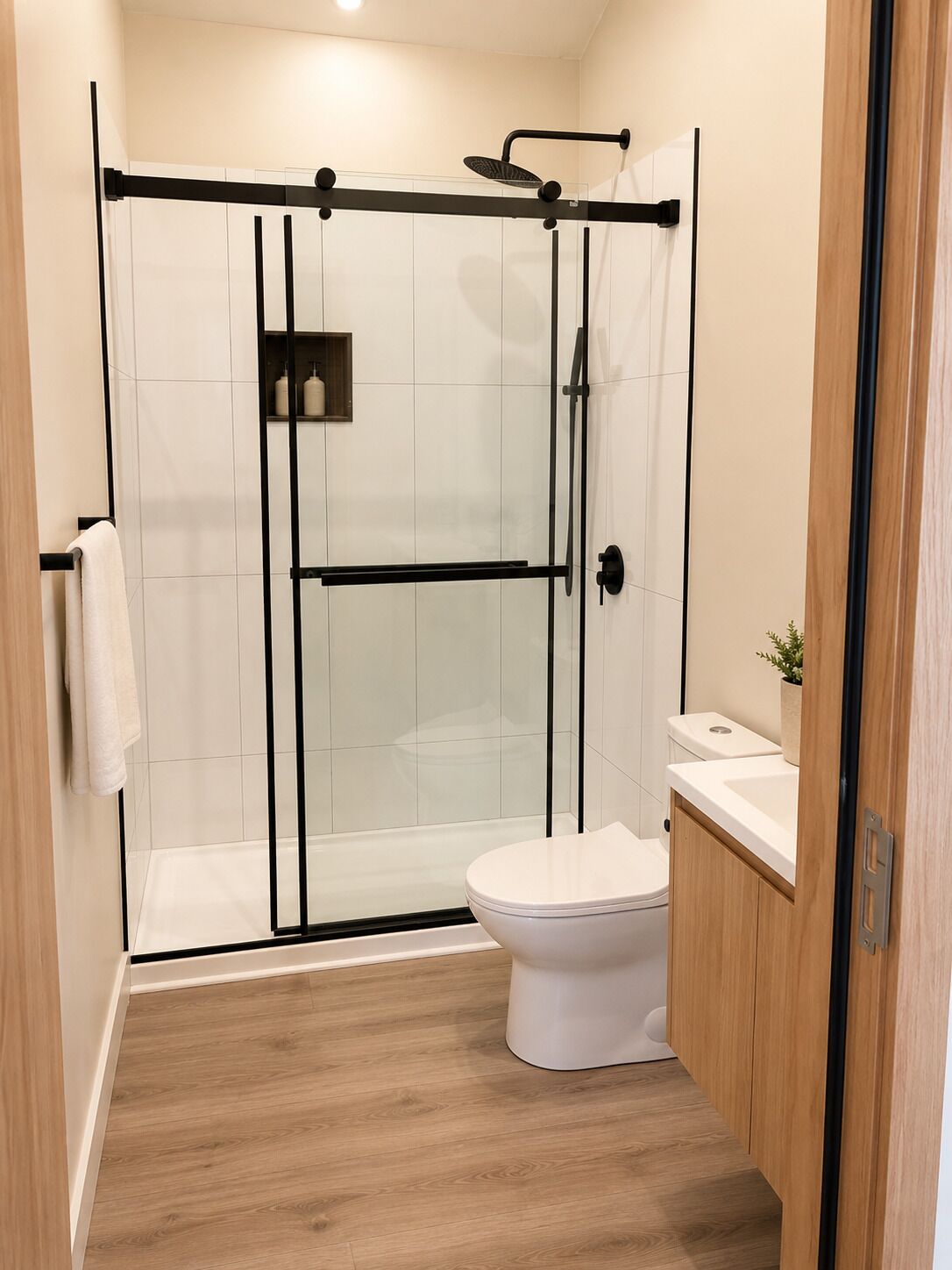 Un baño moderno con ducha de vidrio, inodoro blanco y tocador de madera.
