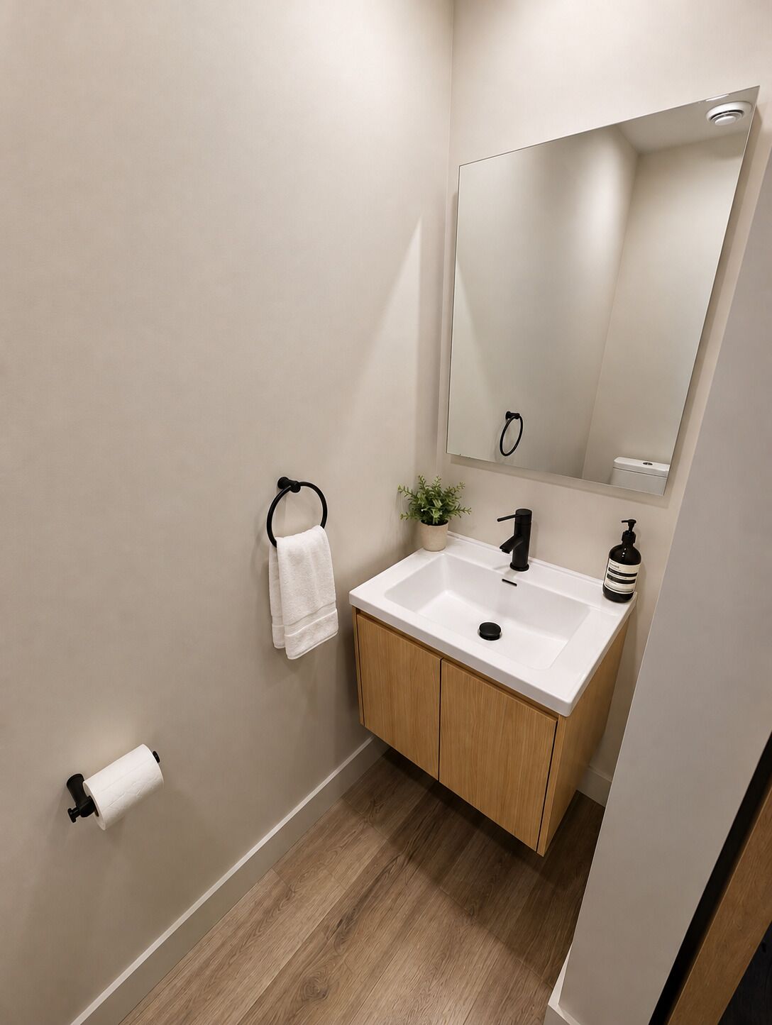 Un bagno moderno con lavandino bianco, mobiletto in legno e specchio.