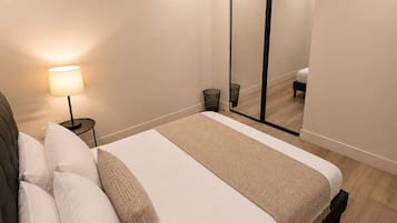 Et moderne soveværelse med seng, sengetlampe og et stort spejl.
