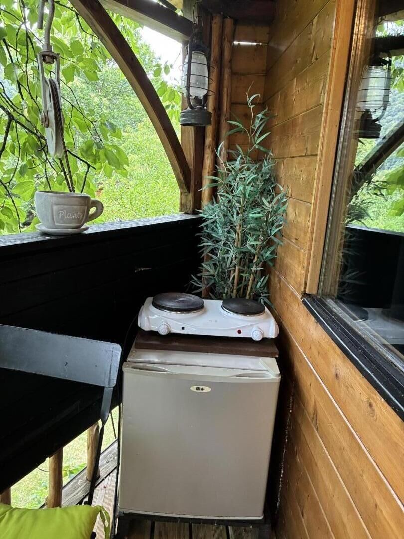 Eine kompakte Küchenzeile mit kleinem Kühlschrank, Herd und Fenster mit Blick auf Grünflächen.