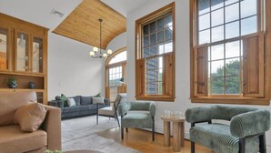 Un salón amplio con techo alto, ventanas grandes y muebles de madera.