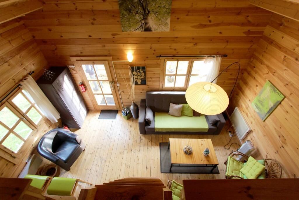 L’intérieur chaleureux d’un chalet avec un canapé, une table à manger, une chaise et un luminaire suspendu.