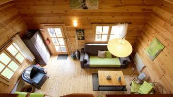 L’intérieur chaleureux d’un chalet avec un canapé, une table à manger, une chaise et un luminaire suspendu.