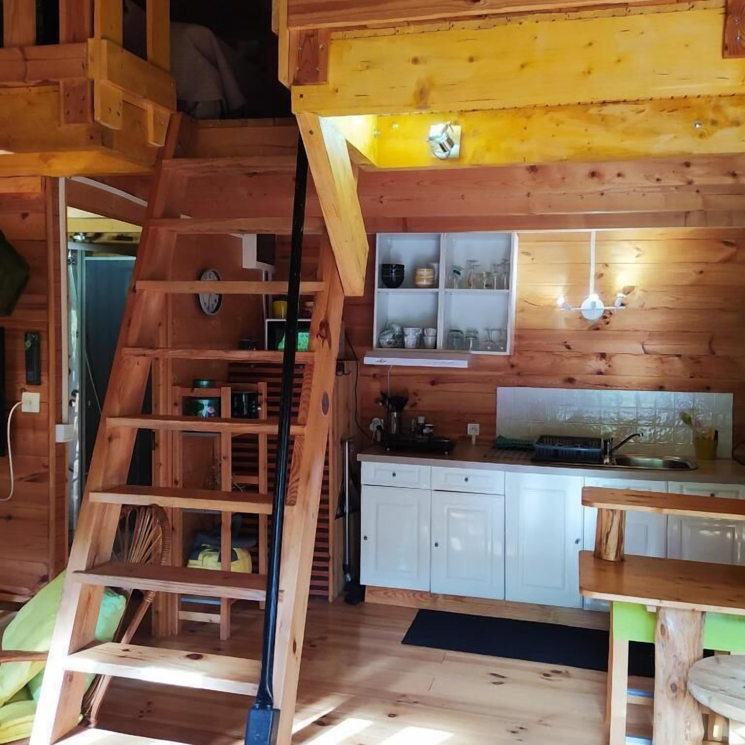 A wooden interior with a kitchen area, a staircase, and a dining table.