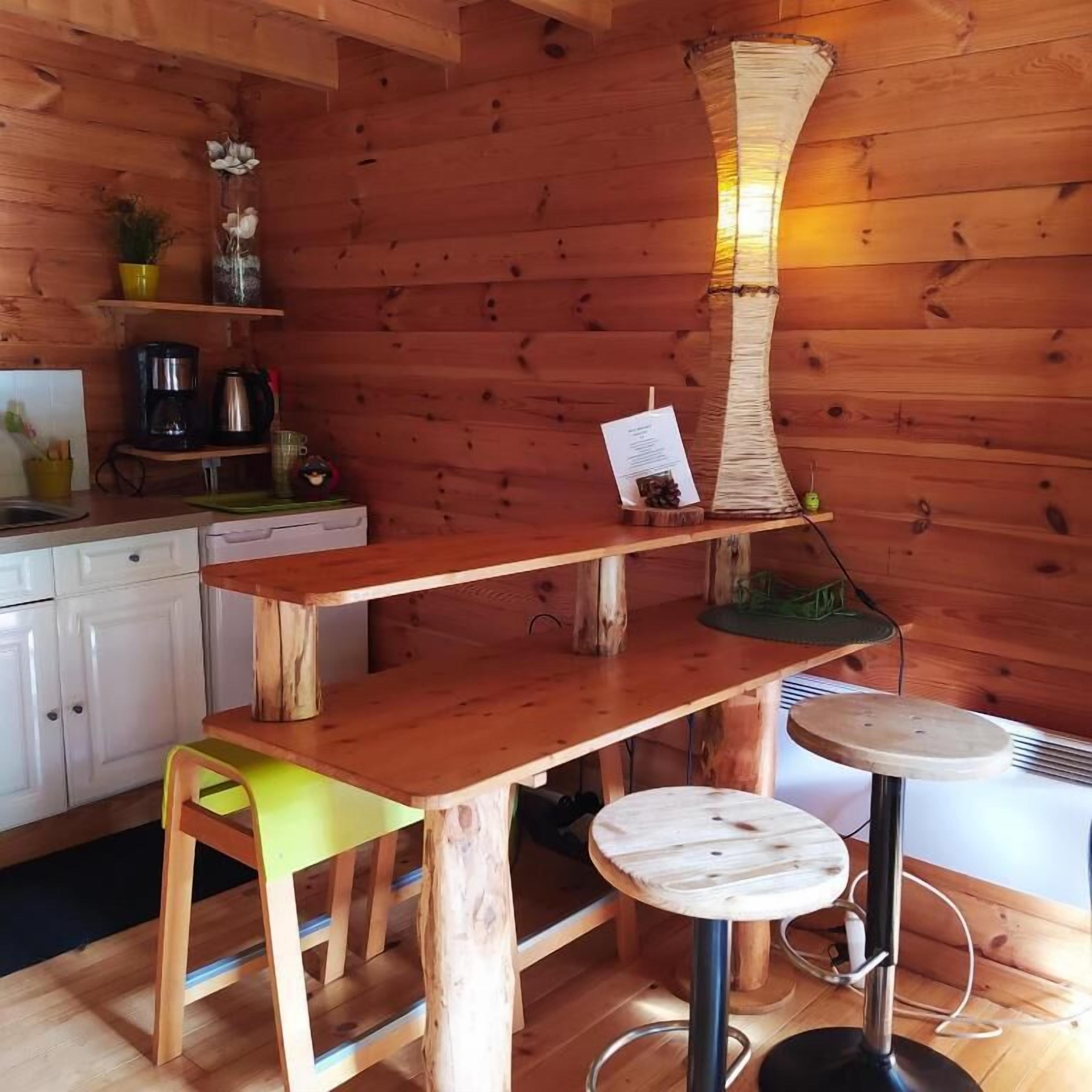 Un intérieur en bois avec une table en bois, un tabouret et une lampe suspendue.
