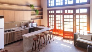 Une cuisine moderne dotée d’un îlot central, de tabourets de bar, de meubles de rangement en bois et d’une grande fenêtre offrant une vue dégagée.