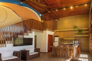 A modern kitchen with a built-in microwave, bar stools, and a large island. - Seaside Retreat w4 Bedrooms and Pool (Caponga)