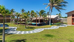 Un complexe hôtelier doté d’une piscine, de palmiers et d’un espace salon abrité.