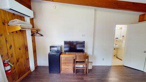 A small room with a wooden desk, a chair, a television, and a white door leading to a bathroom. - Cozy 1-bedroom hotel room in awesome Hamilton - #327 Susquehanna (Hamilton)