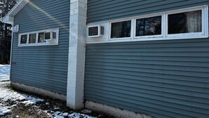 Una casa con facciata grigia, decorazioni bianche e una finestra con cornice bianca.