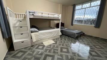 A room with bunk beds, a window, and patterned flooring.