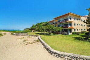 Ein Strandhotel mit Steinmauer, Rasenfläche und freiem Blick auf den Ozean.