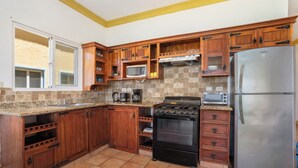 Eine Küche mit Holzschränken, einem Edelstahlkühlschrank, einem Herd und einer Mikrowelle.