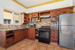 Eine Küche mit Holzschränken, einem Edelstahlkühlschrank, einem Herd und einer Mikrowelle.