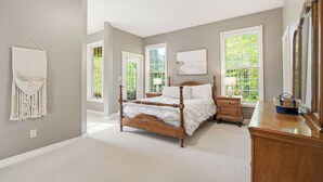 A bedroom with a wooden bed, a dresser, and a macrame wall hanging. - WoodPark Cottage 7bedroom Gamesroom (Lambton Shores)