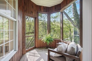 Une pièce en bois avec de grandes fenêtres, un banc et une plante en pot.