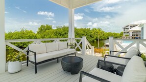 En overdækket terrasse med hvid gelænder, en sofa og et rundt bord.