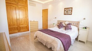Een slaapkamer met een bed, nachtkastjes, een dressoir en een kledingkast.