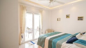 A bedroom with a bed, a ceiling fan, a sliding glass door, and a small table with chairs outside. - Villa Kara Arboleas by Ruralidays (Almería)