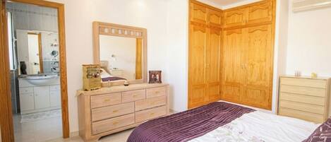 A bedroom with a bed, a dresser, a mirror, and a wardrobe.