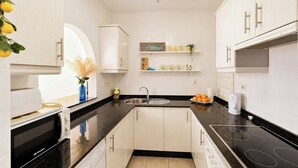 A modern kitchen with white cabinets, a black countertop, a built-in oven, and a sink. - Casa Con Vistas Turre by Ruralidays (Almería)