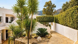 A landscaped outdoor area with palm trees, a stone pathway, and a white building with a number '18' sign. - Casa Con Vistas Turre by Ruralidays (Almería)