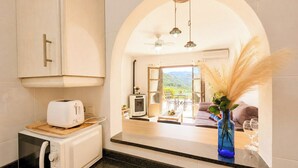 A modern kitchen with a toaster, microwave, and a view into a living area with a fireplace and a sofa. - Casa Con Vistas Turre by Ruralidays (Almería)