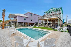 A pool area with lounge chairs and a two-story building with a balcony. - Twin Palms - Unit 1 - 2 Bedroom • 2 Bath - Private Pool - 150 Feet to the Beach (Gulf Shores)