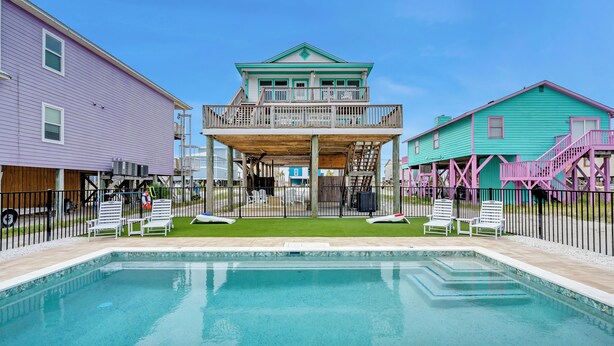 A swimming pool with a wooden deck, surrounded by a fence, and adjacent to a building with a balcony. - Twin Palms - Unit 1 - 2 Bedroom • 2 Bath - Private Pool - 150 Feet to the Beach (Gulf Shores)