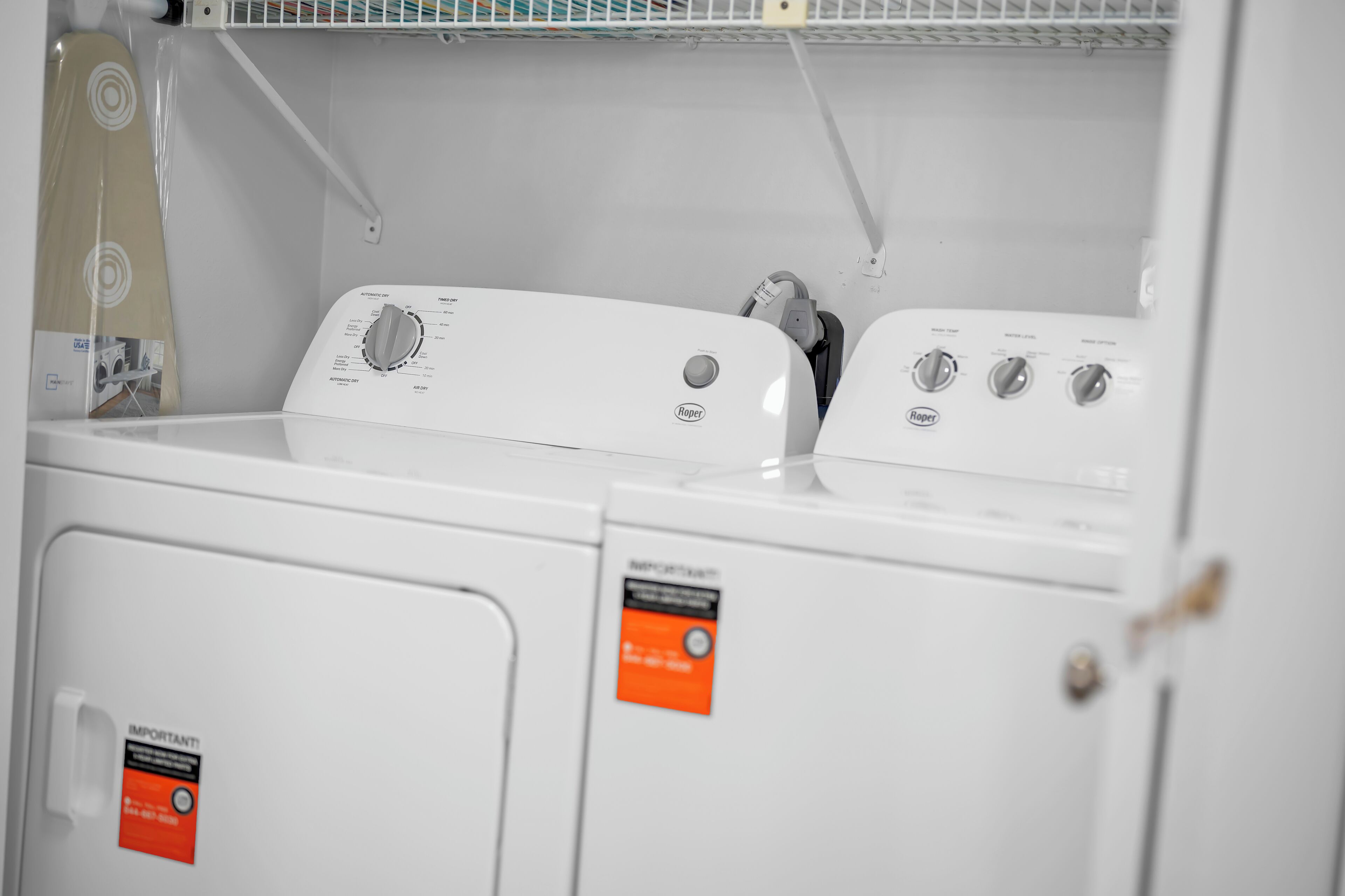 A front view of a white washing machine with a control panel, a dryer, and a tag on the door.