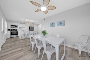 A modern kitchen with white cabinetry, a central island, and a ceiling fan. - Twin Palms - Unit 1 - 2 Bedroom • 2 Bath - Private Pool - 150 Feet to the Beach (Gulf Shores)