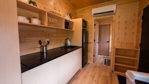 Una cocina compacta con paredes de madera, una encimera negra y un lavabo integrado.