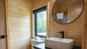 Un baño con paneles de madera, un inodoro, un lavamanos y un espejo.