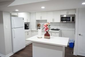 Una cocina moderna con armarios blancos, un microondas de acero inoxidable y una isla central con un florero.