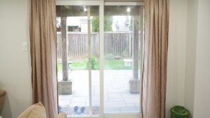 Ein Zimmer mit einer Schiebetür zum Patio, einer grünen Mülltonne und einem beigen Stuhl.