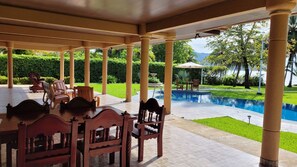 Un espacio al aire libre cubierto con piscina, asientos y vegetación.