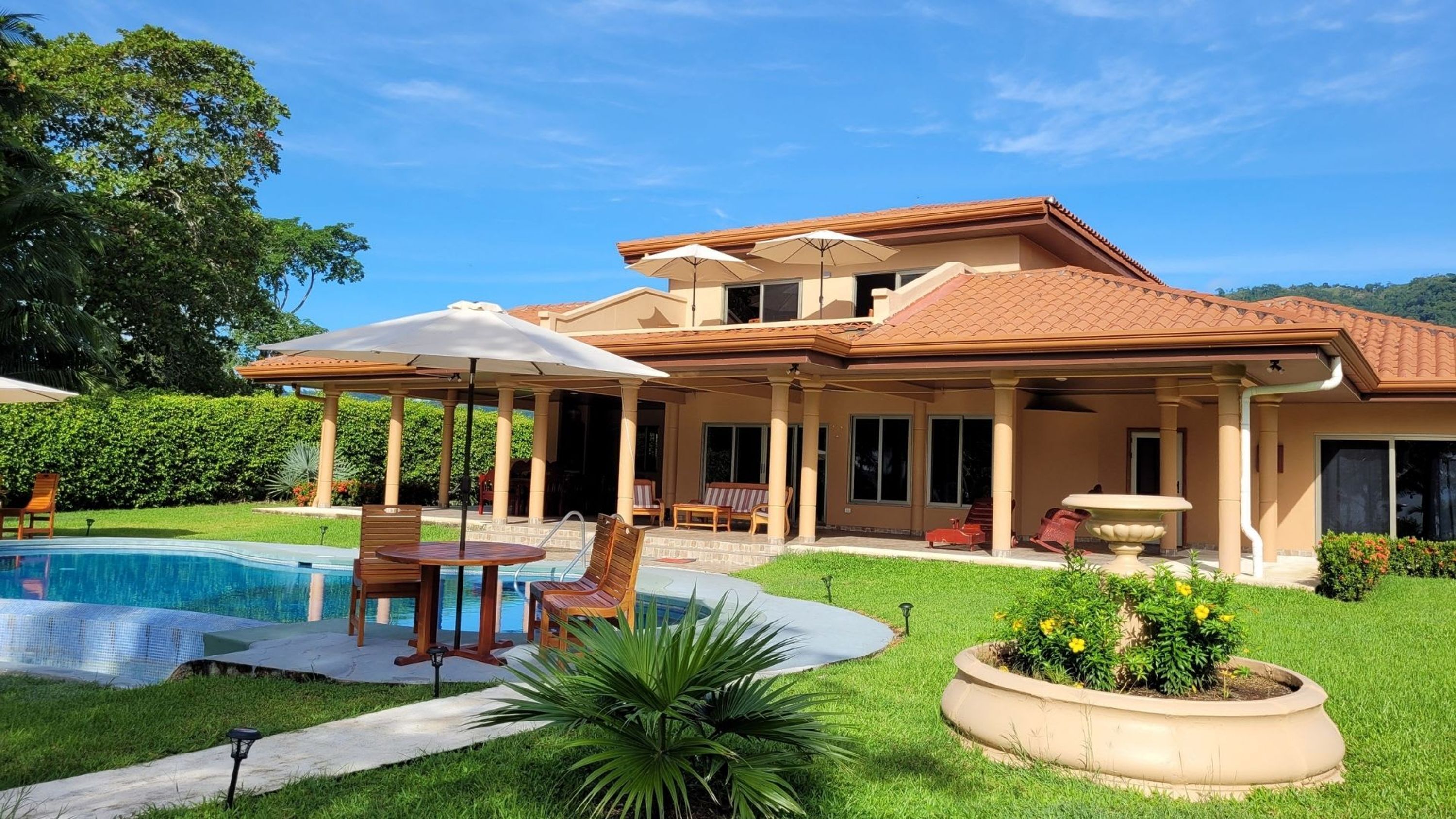 A two-story house with a swimming pool, outdoor seating, and a covered patio area.