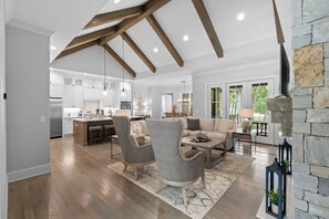 A spacious living area with a kitchen, dining area, and a stone fireplace. - McLemore Resort - 18 Hawthorne Lane - Golf Course View (Rising Fawn)