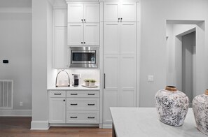 A modern kitchen with white cabinetry, a stainless steel microwave, and a coffee maker on the countertop. - McLemore Resort - 18 Hawthorne Lane - Golf Course View (Rising Fawn)