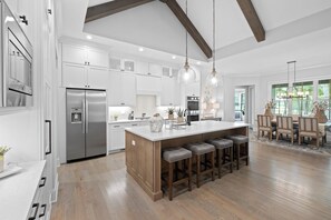 A spacious kitchen with a large island, stainless steel appliances, and wooden bar stools. - McLemore Resort - 18 Hawthorne Lane - Golf Course View (Rising Fawn)