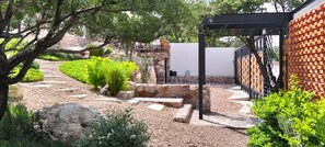 Een tuin met een pad van stenen, een pergola en een bakstenen muur.