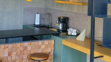 Een moderne keuken met een zwevend kookeiland, een koffieapparaat en een inbouwoven.