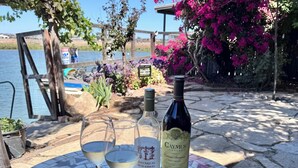 Un tavolo rotondo con un piano in mosaico, due bicchieri da vino e una bottiglia di vino.