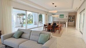 A modern living room with a sofa, dining area, and kitchen. - New Modern Villa: Pool, BBQ, Sea View & Movie Room (TIVAT)
