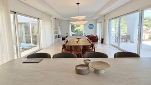 A modern dining area with a large table, chairs, and a view of the outdoors. - New Modern Villa: Pool, BBQ, Sea View & Movie Room (TIVAT)